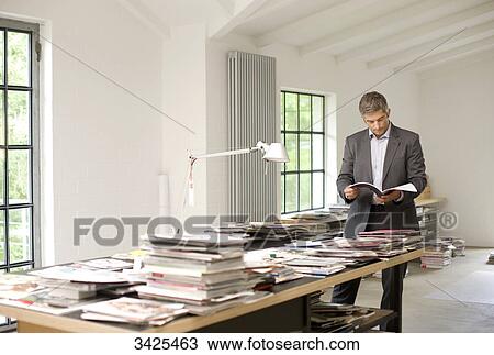 Stock Image - Man reading a magazines in an office . Fotosearch