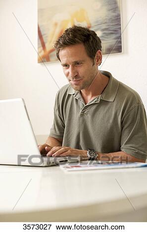 Stock Photo - Man using laptop at table . Fotosearch