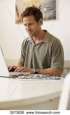 Stock Photograph - Man using laptop at table . Fotosearch