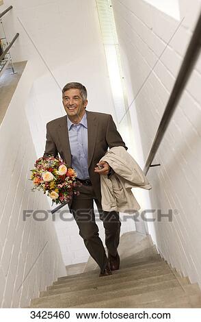 Stock Image - Man with a bouquet walking upstairs, elevated view . Fotosearch