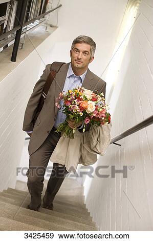 Stock Photo - Man with a bouquet walking upstairs, elevated view . Fotosearch