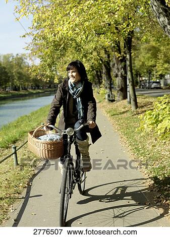 Mature woman cycling along river View Large Photo Image Stock Photo - Mature woman cycling along river . Fotosearch