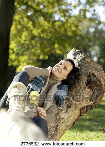 Mature woman resting on fallen tree and smiling View Large Photo Image Stock Image - Mature woman resting on fallen tree and smiling . Fotosearch