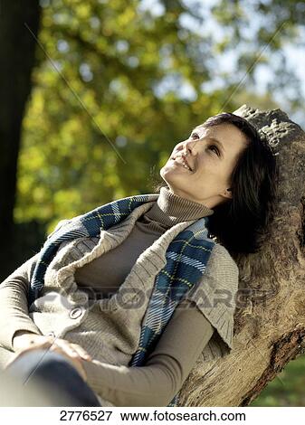 Mature woman sitting on fallen tree and smiling View Large Photo Image Stock Photo - Mature woman sitting on fallen tree and smiling . Fotosearch