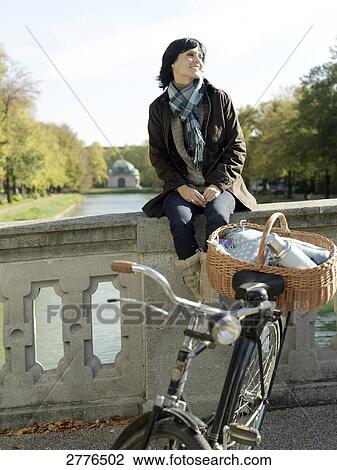 Mature woman sitting on wall of bridge View Large Photo Image Stock Image - Mature woman sitting on wall of bridge . Fotosearch