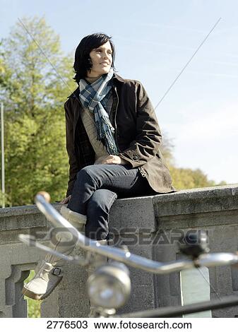 Mature woman sitting on wall of bridge View Large Photo Image Stock Image - Mature woman sitting on wall of bridge . Fotosearch