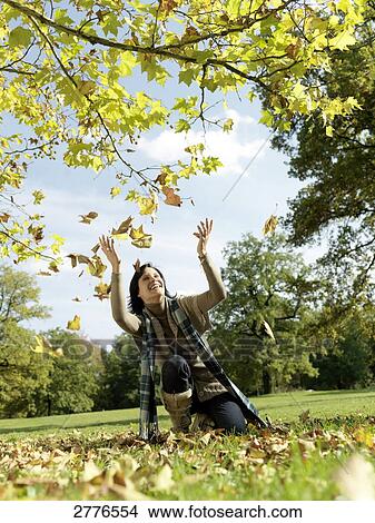 Mature woman throwing leaves and smiling in park View Large Photo Image Picture - Mature woman throwing leaves and smiling in park . Fotosearch