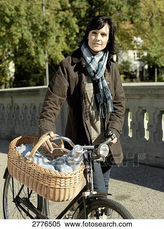 Stock Photography - Mature woman walking with bicycle on bridge . Fotosearch