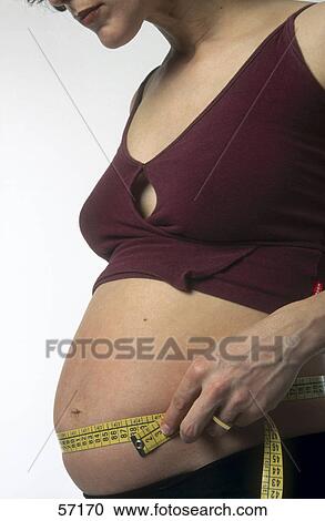 Mid section view of pregnant woman measuring her abdomen View Large Photo Image Stock Image - Mid section view of pregnant woman measuring her abdomen . Fotosearch