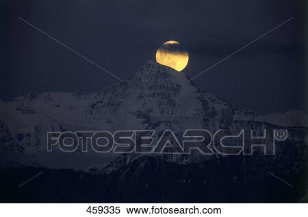 Stock Photography - Moon over snow covered mountain, Bernese Oberland, Switzerland . Fotosearch