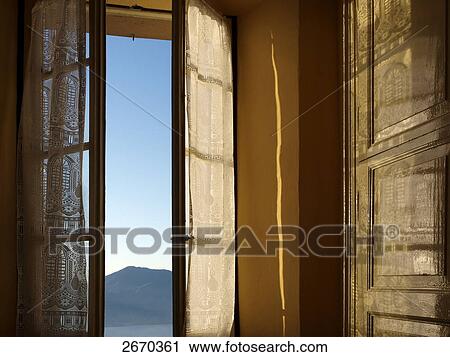 Stock Image - Mountain viewed through hotel window, Lago Maggiore, Piedmont, Italy . Fotosearch