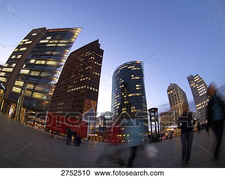 Stock Image - People standing in front of lit up buildings, Kollhoff Tower, BahnTower, Berlin, Germany . Fotosearch