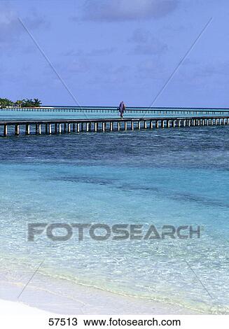 Stock Image - Person walking on a pier, Maldives . Fotosearch