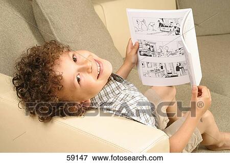 Stock Photo - Portrait of a boy holding a comic book and smiling . Fotosearch