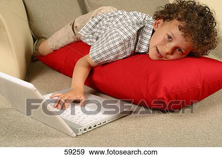 Portrait of boy using laptop on couch View Large Photo Image Stock Photo - Portrait of boy using laptop on couch . Fotosearch