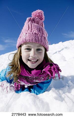 Stock Image - Portrait of girl lying on snow and smiling . Fotosearch