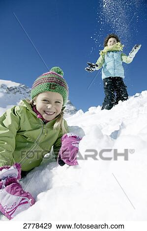 Portrait of girl smiling on snowcovered landscape with boy in background View Large Photo Image Stock Photo - Portrait of girl smiling on snowcovered landscape with boy in background . Fotosearch