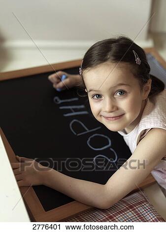 Stock Image - Portrait of girl writing on chalkboard and smiling . Fotosearch