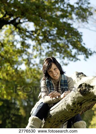 Portrait of mature woman sitting on fallen tree and smiling View Large Photo Image Stock Image - Portrait of mature woman sitting on fallen tree and smiling . Fotosearch