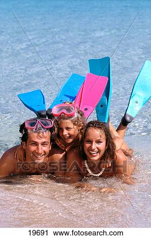 Stock Image - Portrait of parents and their daughter lying in shallow water . Fotosearch