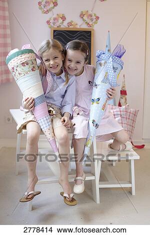 Portrait of two girls holding cardboard cones and smiling on table View Large Photo Image Picture - Portrait of two girls holding cardboard cones and smiling on table . Fotosearch