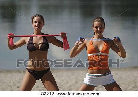 Stock Image - Portrait of two young women doing yoga on lake beach . Fotosearch
