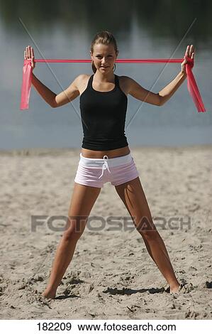 Stock Photo - Portrait of young woman doing yoga on lake beach . Fotosearch