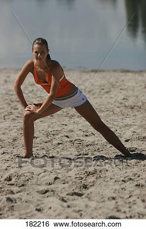 Stock Photograph - Portrait of young woman doing yoga on lake beach . Fotosearch