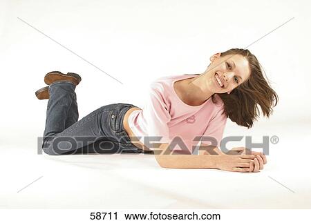 Stock Image - Portrait of young woman lying on floor and smiling . Fotosearch