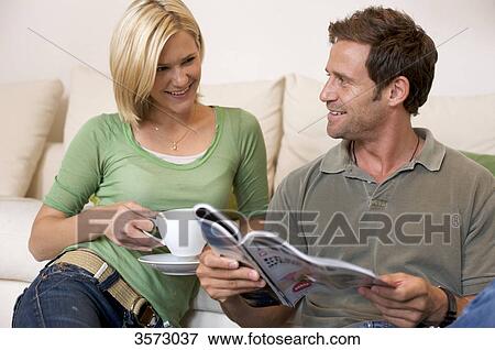Relaxed couple at home with magazine and coffee View Large Photo Image Stock Photo - Relaxed couple at home with magazine and coffee . Fotosearch