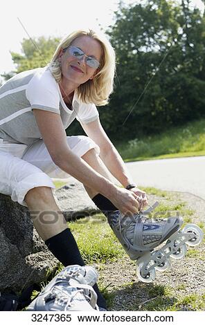 Stock Photography - Senior woman tightening Inline-Skates, slanted view . Fotosearch