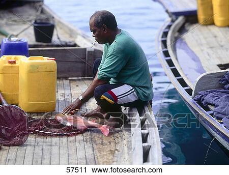 Stock Image - Side profile of fisherman smoking cigarette on boat, Maldives . Fotosearch