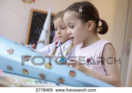 Side profile of two girls making cardboard cone View Large Photo Image Stock Photography - Side profile of two girls making cardboard cone . Fotosearch