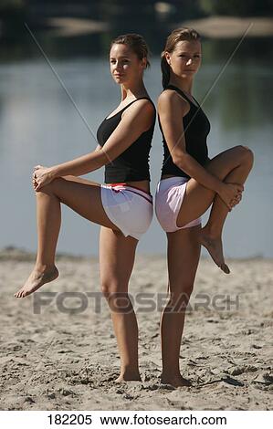 Side profile of two young women doing yoga on lake beach View Large Photo Image Stock Photography - Side profile of two young women doing yoga on lake beach . Fotosearch
