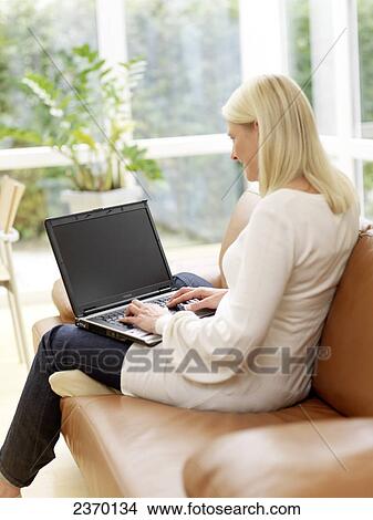 Side profile of woman using laptop on couch View Large Photo Image Picture - Side profile of woman using laptop on couch . Fotosearch