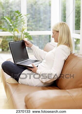 Side profile of woman using laptop on couch View Large Photo Image Stock Image - Side profile of woman using laptop on couch . Fotosearch
