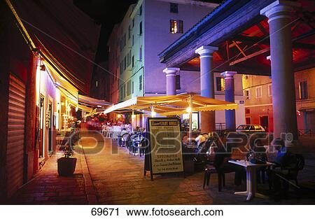 Stock Image - Sidewalk cafe lit up at night, France . Fotosearch