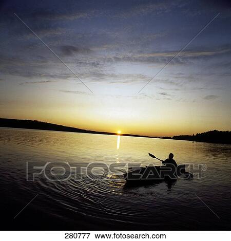 Stock Photo - Silhouette of person boating in river at dusk . Fotosearch