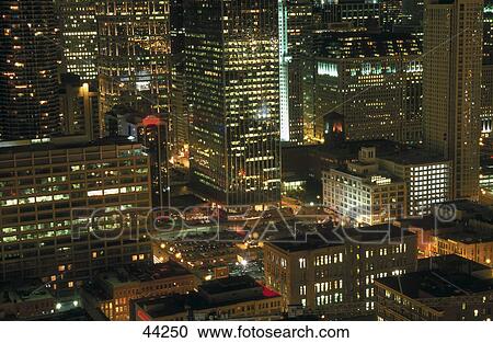 Stock Image - Skyscrapers in city lit up at night, Chicago, Illinois, USA . Fotosearch