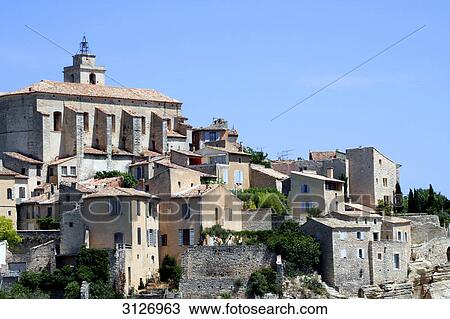 Stock Image - Stone houses and church in Gordes, France, low angle view . Fotosearch