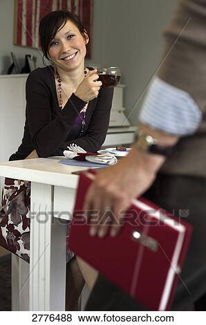 Stock Photo - Teenage girl holding cup of tea and smiling at table . Fotosearch
