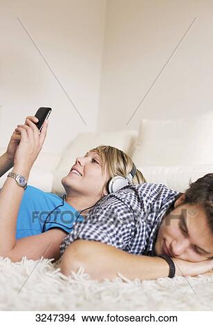 Teenager couple lying on carpet and listening to music, low-angle view  View Large Photo Image Picture - Teenager couple lying on carpet and listening to music, low-angle view . Fotosearch