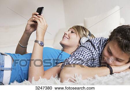 Teenager couple lying on carpet and listening to music, low-angle view View Large Photo Image Stock Image - Teenager couple lying on carpet and listening to music, low-angle view . Fotosearch