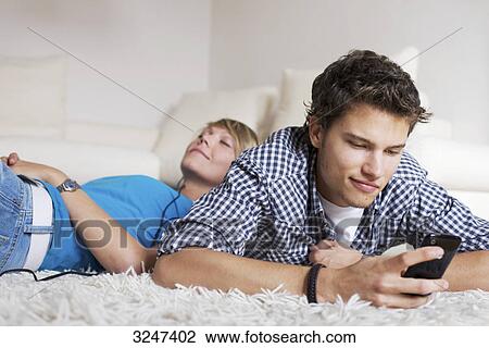 Teenager couple lying on carpet and listening to music, low-angle view View Large Photo Image Stock Image - Teenager couple lying on carpet and listening to music, low-angle view . Fotosearch