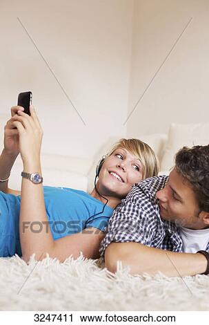 Teenager couple lying on carpet and listening to music, low-angle view View Large Photo Image Stock Image - Teenager couple lying on carpet and listening to music, low-angle view . Fotosearch