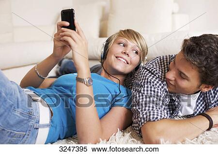 Teenager couple lying on carpet and listening to music, low-angle view View Large Photo Image Stock Photography - Teenager couple lying on carpet and listening to music, low-angle view . Fotosearch