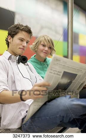 Stock Image - Teenager couple readung newspaper at underground, low-angle view . Fotosearch