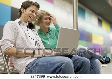 Stock Photo - Teenager couple using laptop at underground station, low-angle view . Fotosearch