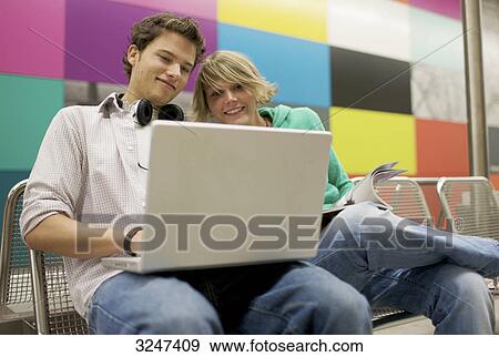 Stock Photo - Teenager couple using laptop at underground station, low-angle view . Fotosearch