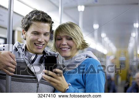 Teenager couple using mobile phone in metro, waist up View Large Photo Image Stock Image - Teenager couple using mobile phone in metro, waist up . Fotosearch